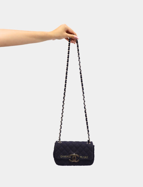 Chanel black quilted flap bag with oversized silver-tone CC logo and leather-woven chain strap.