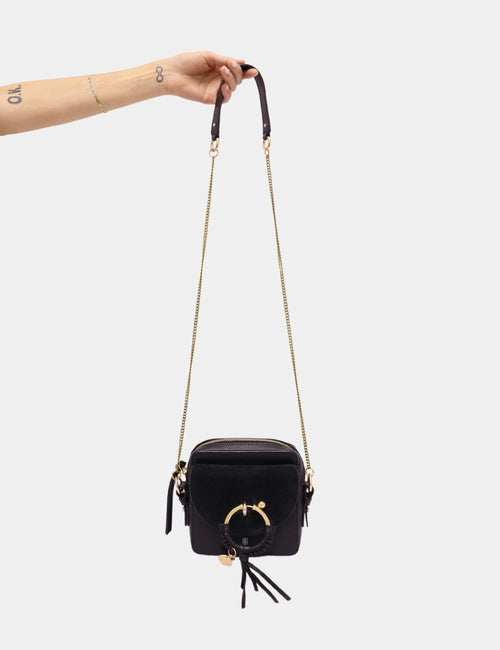See by Chloé black leather mini crossbody bag with gold ring, tassel detail, and chain strap.