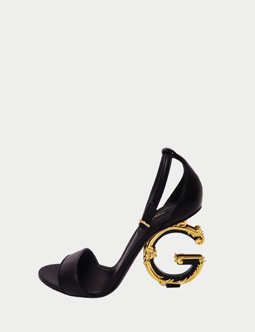Dolce & Gabbana black leather sandals with sculpted gold baroque heel and ankle strap, luxury Italian designer footwear.