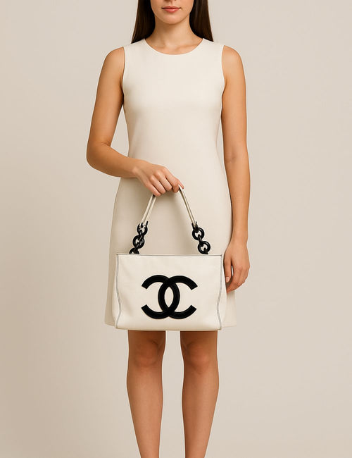 Chanel white leather tote bag with oversized black CC logo and black resin chain accents.