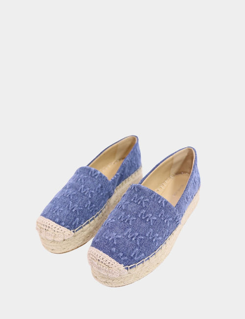"Michael Kors blue denim monogram platform espadrilles with jute sole and crochet toe detail on white background."