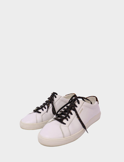 Saint Laurent white leather low-top sneakers with animal print laces and gold logo detail on side.