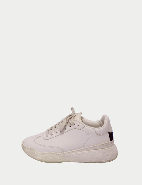 Stella McCartney white low-top sneakers with lace-up front, chunky textured sole, and navy blue heel tab detail