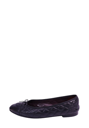 Black Chanel quilted lambskin ballet flats featuring a cap-toe design, signature interlocking CC logo detail on the toe, bow accent, leather lining, and flat sole. Classic slip-on silhouette with diamond quilting throughout the upper