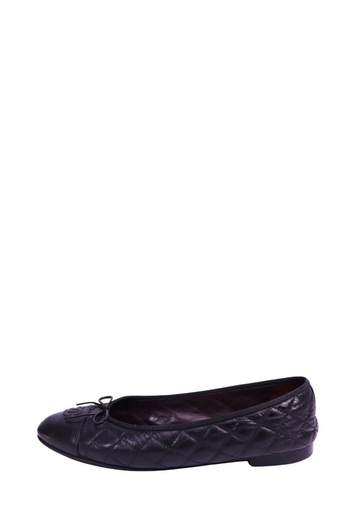 Black Chanel quilted lambskin ballet flats featuring a cap-toe design, signature interlocking CC logo detail on the toe, bow accent, leather lining, and flat sole. Classic slip-on silhouette with diamond quilting throughout the upper