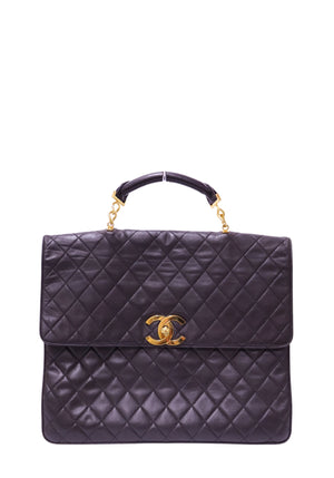 Authentic Chanel Maxi Classic Flap Top Handle bag in black quilted lambskin leather with gold-tone CC turn-lock hardware.