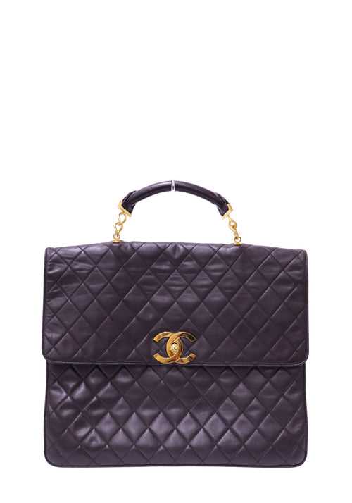 Authentic Chanel Maxi Classic Flap Top Handle bag in black quilted lambskin leather with gold-tone CC turn-lock hardware.