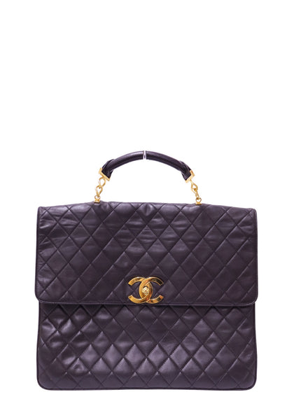 Authentic Chanel Maxi Classic Flap Top Handle bag in black quilted lambskin leather with gold-tone CC turn-lock hardware.