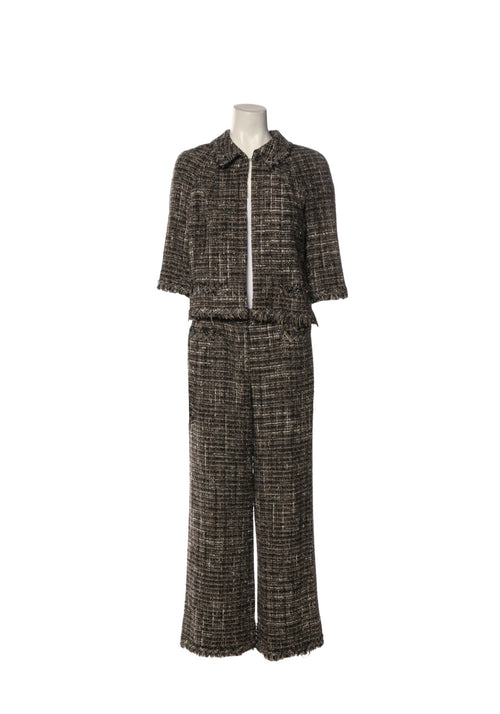 Authentic Chanel black and ivory tweed two-piece set featuring a cropped fringe-trim jacket with front patch pockets and matching cropped wide-leg trousers