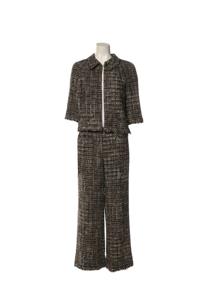 Authentic Chanel black and ivory tweed two-piece set featuring a cropped fringe-trim jacket with front patch pockets and matching cropped wide-leg trousers