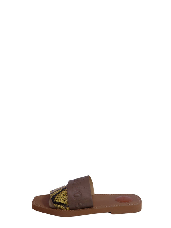 Chloé beige leather flat slide sandals featuring embossed logo straps, yellow and black python-print leather accents, cushioned leather footbeds, and a minimalist slip-on design.