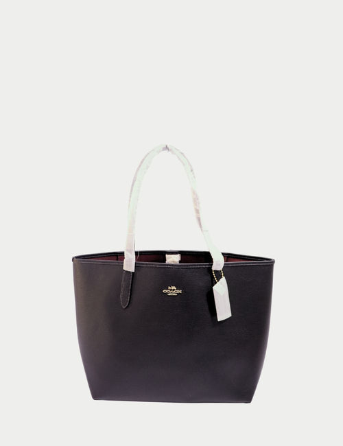 Coach black leather tote bag with dual top handles, gold-tone logo detail, and spacious open interior