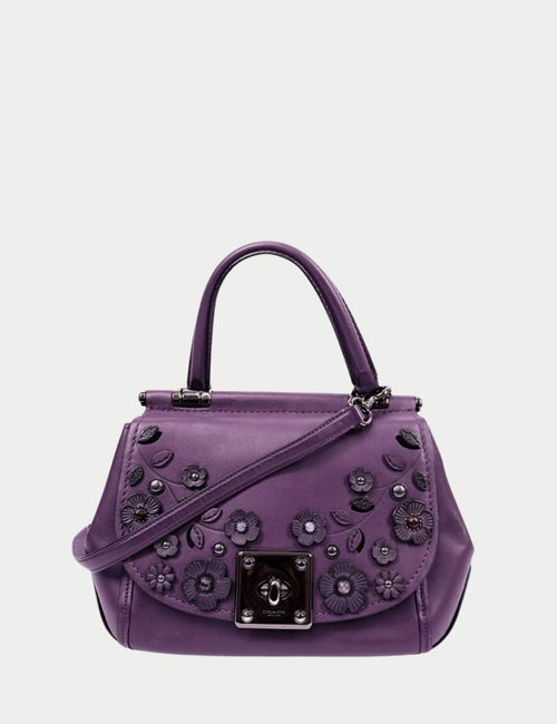 Coach purple leather top handle bag with floral appliqué, silver turn-lock closure, and detachable shoulder strap