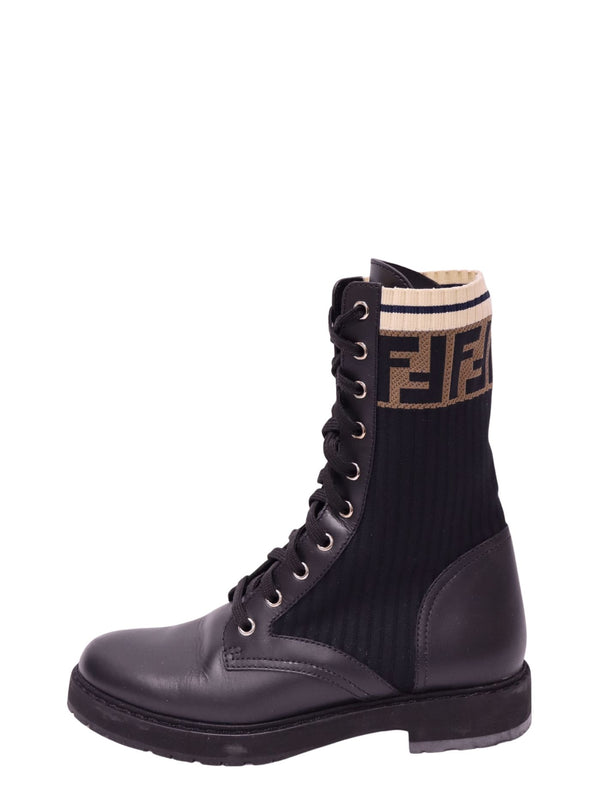 Fendi black leather lace-up combat boot featuring ribbed black knit shaft, brown FF monogram logo, cream striped cuff, silver-tone eyelets, and chunky rubber sole
