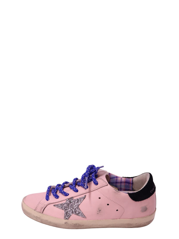 Authentic Golden Goose Superstar pink leather sneakers with a silver glitter star, blue laces, black heel tab, and distressed rubber sole.