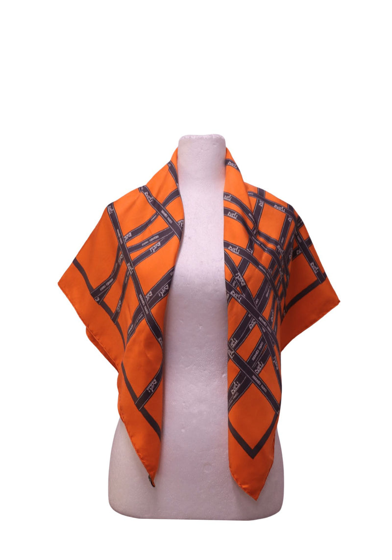 Authentic Hermès orange silk square scarf featuring an interwoven ribbon print with Hermès Paris branding and hand-rolled edges