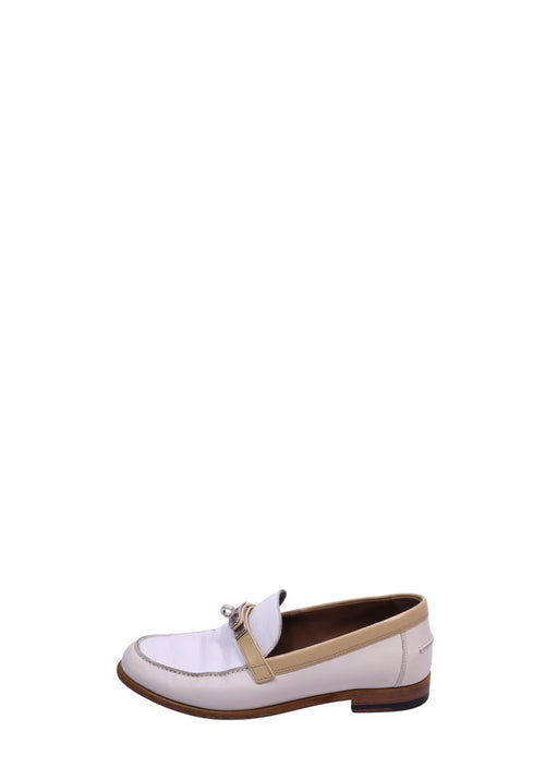 Hermès white leather loafers featuring beige trim, signature buckle detail, and a low stacked heel