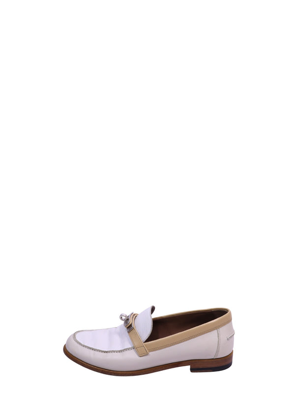 Hermès white leather loafers featuring beige trim, signature buckle detail, and a low stacked heel
