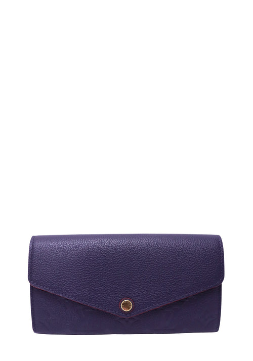 Louis Vuitton Sarah Wallet in navy Monogram Empreinte leather with red trim and gold-tone snap closure.