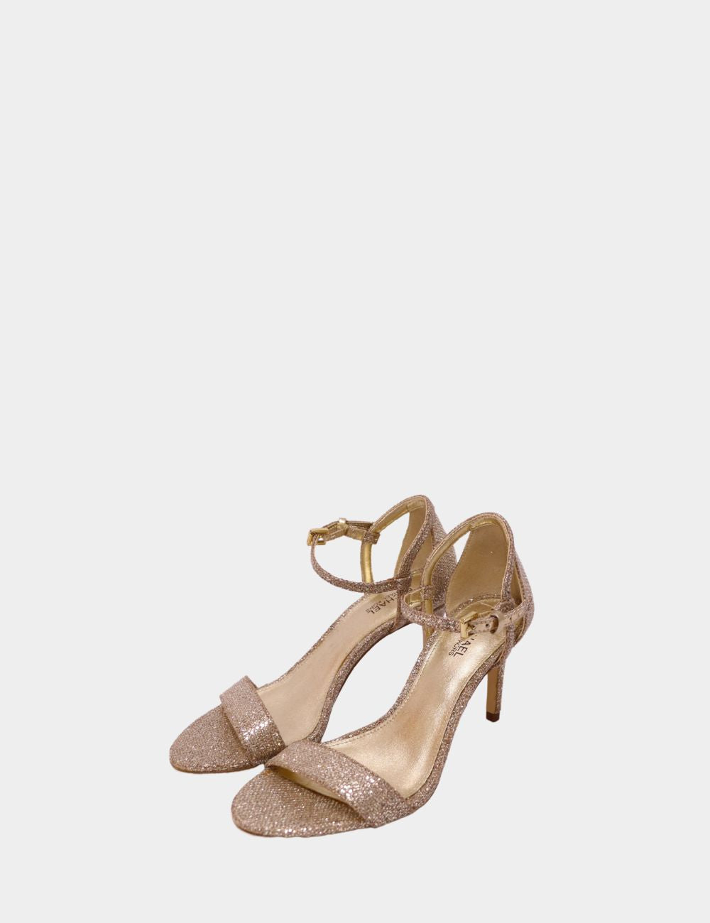 Step into timeless elegance with the Michael Kors Gold Shimmer Strappy Heel, a perfect blend of sophistication and sparkle. Crafted with a delicate ankle strap and secure buckle fastening, this mid-heel sandal offers both comfort and glamour. Its shimmeri Step into timeless elegance with the Michael Kors Gold Shimmer Strappy Heel, a perfect blend of sophistication and sparkle. Crafted with a delicate ankle strap and secure buckle fastening, this mid-heel sandal offers both comfort and glamour. Its shimmeri