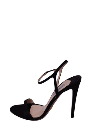 Prada black suede high-heel sandal featuring a minimalist open-toe front strap, delicate ankle strap, sculptural slingback-style detailing, nude insole, and slender black stiletto heel
