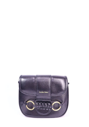 See by Chloé Saddie black leather crossbody bag featuring gold-tone ring hardware, braided leather detailing, and a curved flap-front design