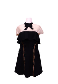 Authentic Self-Portrait black and cream mini dress featuring a contrast mesh yoke, black bow neckline, layered ruffle bodice, lattice cutout side panels, and a flattering A-line silhouette.