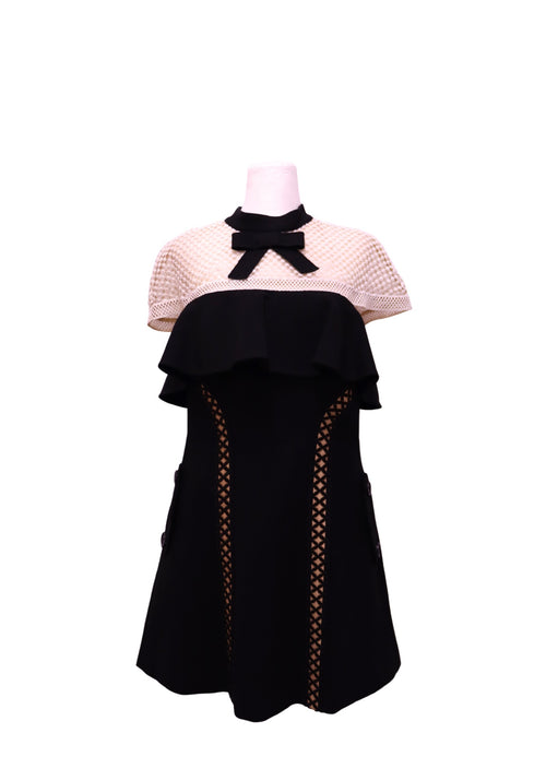 Authentic Self-Portrait black and cream mini dress featuring a contrast mesh yoke, black bow neckline, layered ruffle bodice, lattice cutout side panels, and a flattering A-line silhouette.