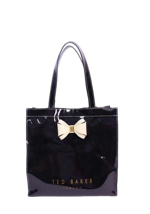 Ted Baker black patent tote bag featuring a glossy finish, signature cream bow detail, gold logo lettering, and dual shoulder straps