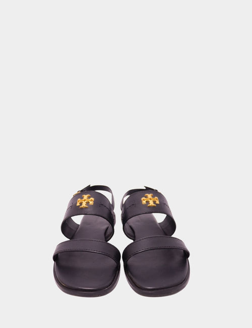 Tory Burch black leather flat sandals with gold-tone logo on strap, displayed front-facing on a plain background