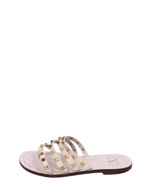 Valentino Garavani Rockstud white leather flat sandals with multiple straps and gold pyramid studs.