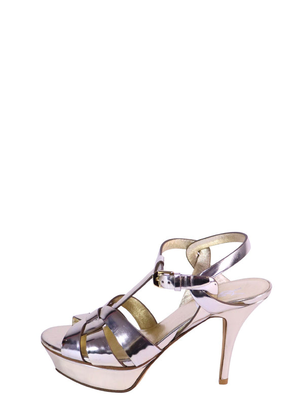 Saint Laurent silver metallic platform sandals with crossover straps and high stiletto heels.