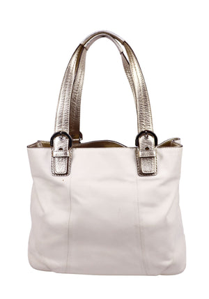 Coach cream leather tote bag with metallic champagne shoulder straps and minimalist design.