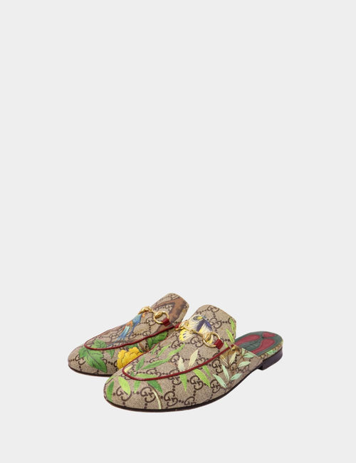 Gucci GG monogram slipper loafers with colorful floral and bird print, featuring gold horsebit detail and backless slip-on design.