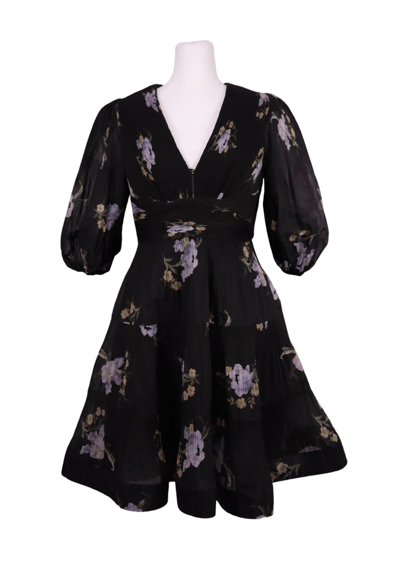 Authentic Zimmermann black floral mini dress with lilac floral print, deep V-neckline, voluminous sleeves, and pleated flowing skirt.
