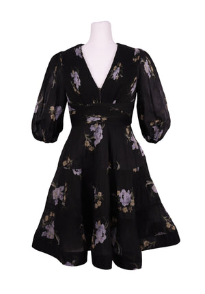 Authentic Zimmermann black floral mini dress with lilac floral print, deep V-neckline, voluminous sleeves, and pleated flowing skirt.